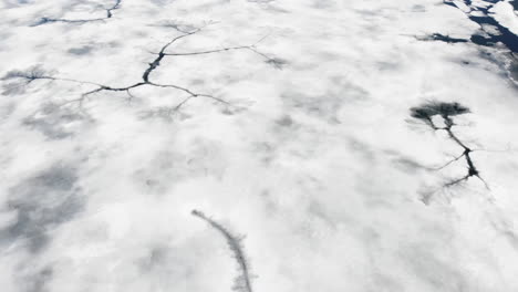 Aerial-of-Frozen-Lake-Top-Down,-Tilts-Up-to-Snowy-Mountain-Landscape