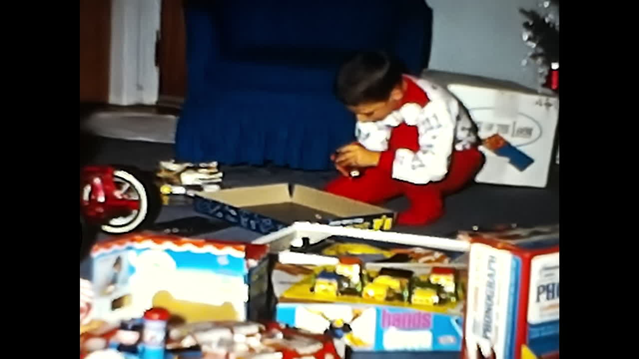 Small Child Engages With Toys on Floor. CIRCA USA - 1970s: A small child in a 1970s video archive from the USA is actively playing with toys on the floor.