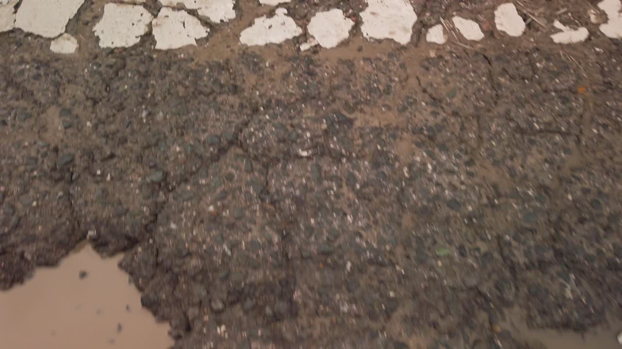 caminar sobre un paso de peatones agrietado con baches, cerrar de arriba hacia abajo