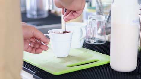 stirring hot chocolate powder into a white cup