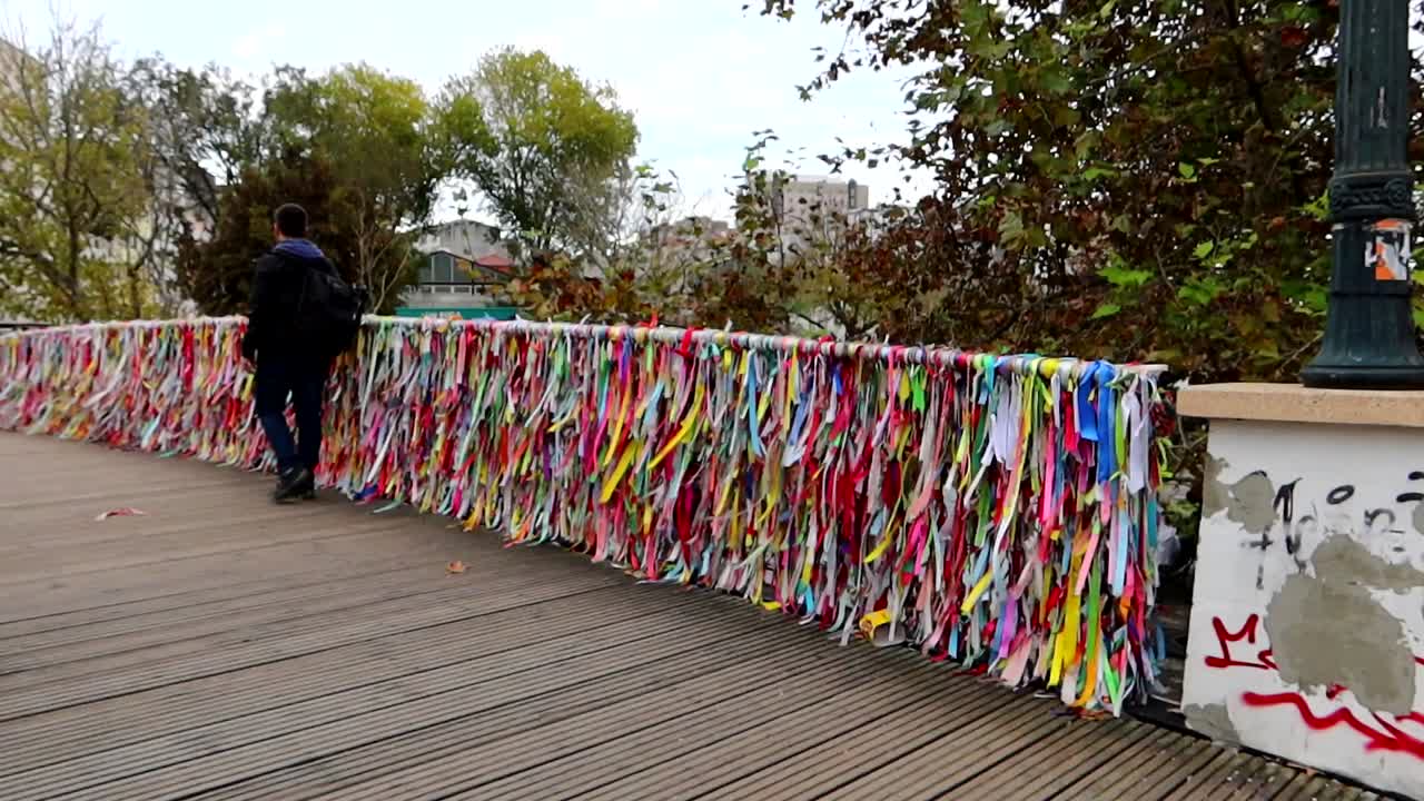 Tourist strolling beside the wooden Ponte La&ccedil;os de Amizade with colorful banners swaying in the breeze