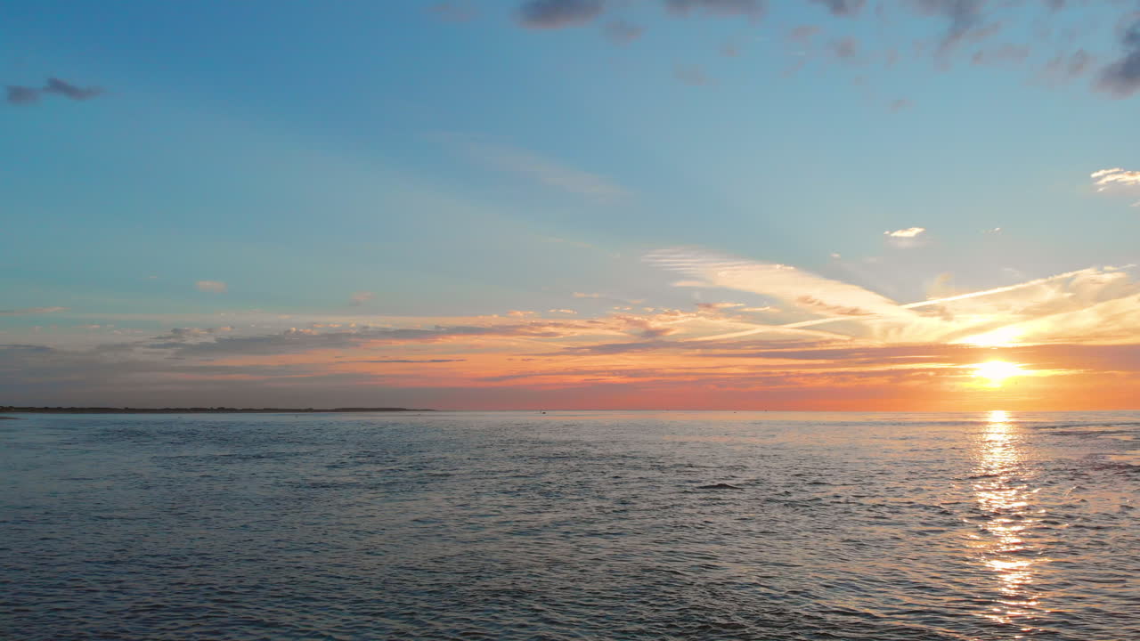 una marea baja tranquila en la playa cerca de la barrera de marejada en el suroeste de los países bajos, durante la puesta de sol