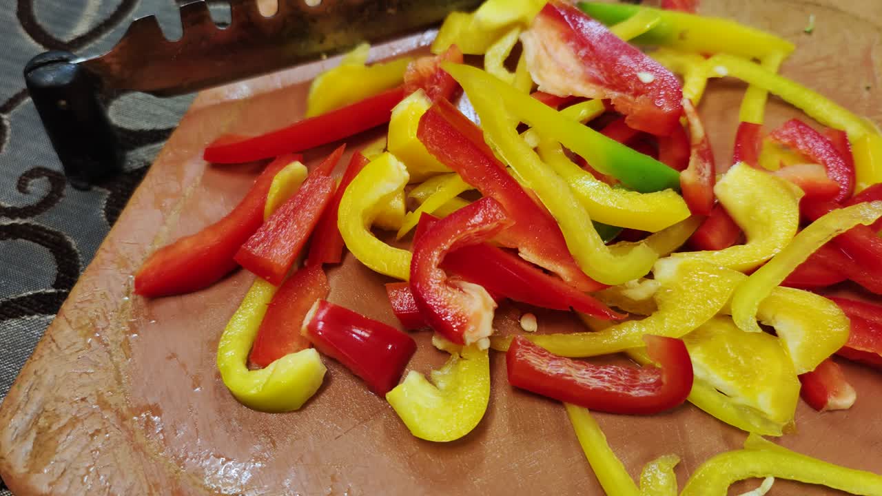 신선한 빨간색과 노란색 고추는 스테인리스 스 칼날로 갈색 채소 절단기에 어