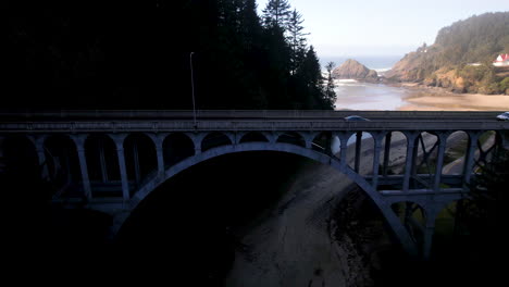 a drone lifting next to the cape creek bridge with lighthouse in the background