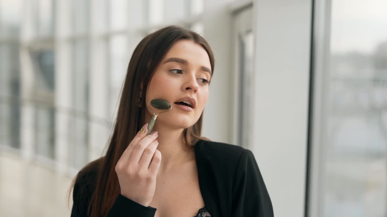 retrato de una chica muy sonriente haciendo un masaje facial con un rodillo de masaje