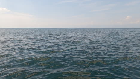 flat horizon line on large body of water, lake or ocean, wispy cloud