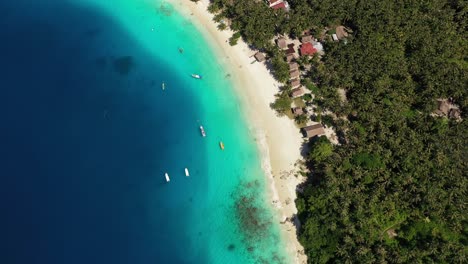 Vista-Aérea-De-La-Isla-Tropical-Con-Bungalows-En-La-Playa-Y-Asombrosas-Aguas-Turquesas-En-Indonesia---Cámara-Girando-Lentamente