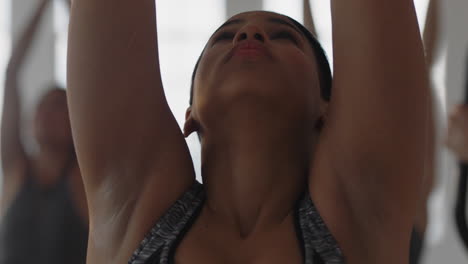 retrato de una mujer de yoga de raza mixta practicando meditación en pose de oración con un grupo de mujeres multirraciales disfrutando de un estilo de vida saludable haciendo ejercicio en un gimnasio al amanecer.