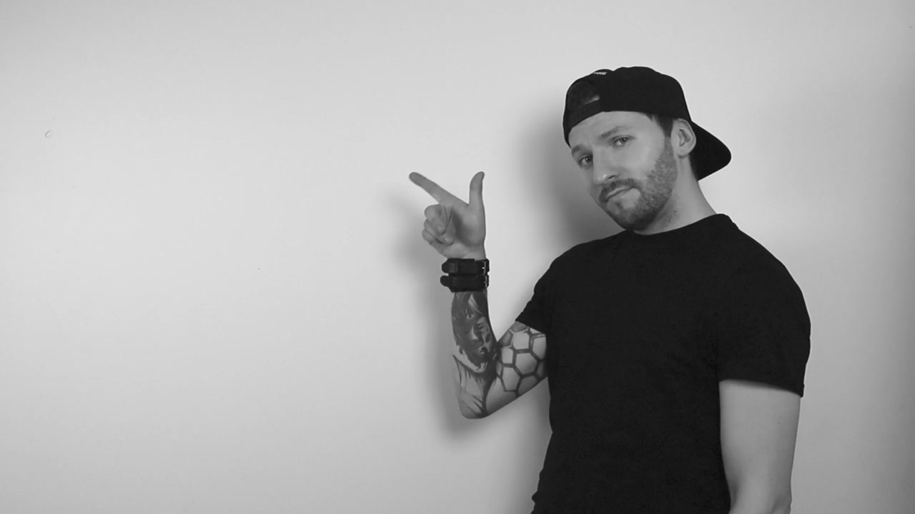 Filmato in scala di grigi di un uomo tatuato che riflette su qualcosa con cui è d'accordo annuendo, indica l'angolo superiore sinistro vuoto con il dito e continua ad annuire e ad essere felice.