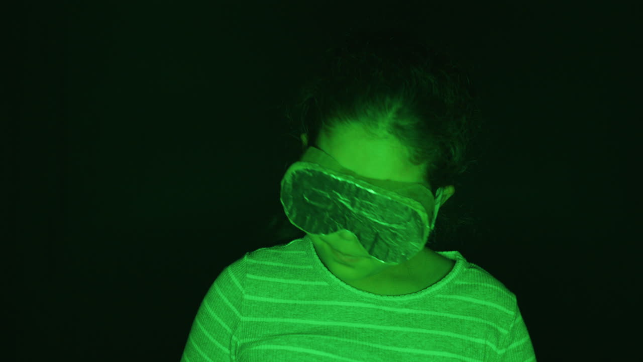 Bambino con visore di realtà virtuale in cartone e forte luce verde che finge di essere in VR