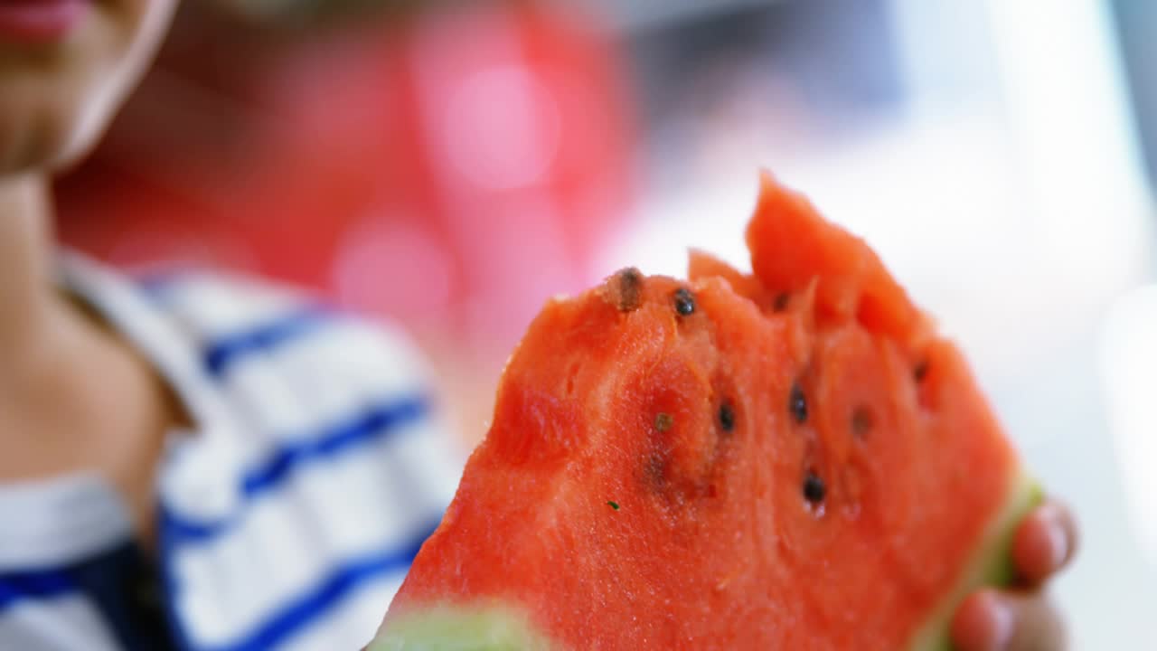 Boy lifting watermelon slice to mouth as floating technology labels emerging, counts increasing
