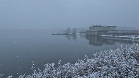 Starker-Schneefall-über-Einem-Wunderschönen-Stausee-Und-Dem-Nahegelegenen-Damm