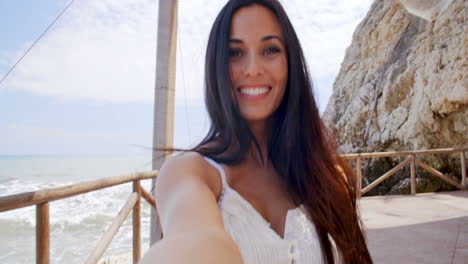 brunette woman taking self portrait by ocean