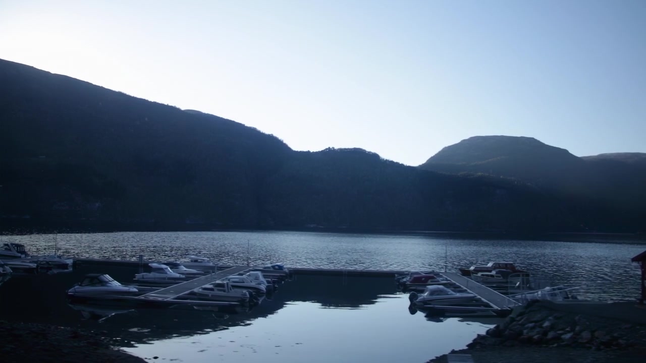 Passerer marina ved innsjøen og byggematerialer i skumringen, med fjellene i Nærøydalen i bakgrunnen.