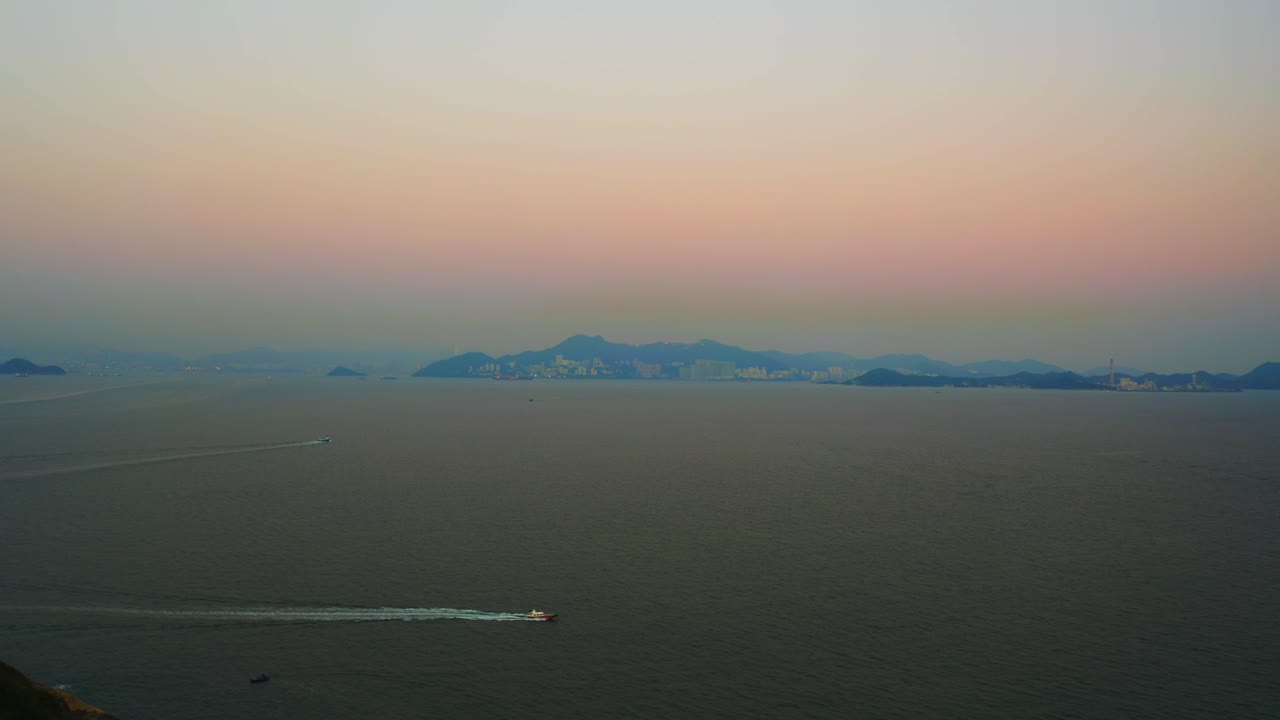 Drone shot of the sea during a very polluted day, the sun barely go through the atmosphere. Some boat are passing by and there is an island in the distance.