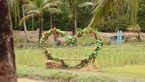 a heart-shaped floral frame stands in a lush, tropical setting with gentle camera movement and natural lighting