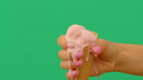 lapso de tiempo de una mano femenina sosteniendo un cono de helado derretido en fondo verde, 4k