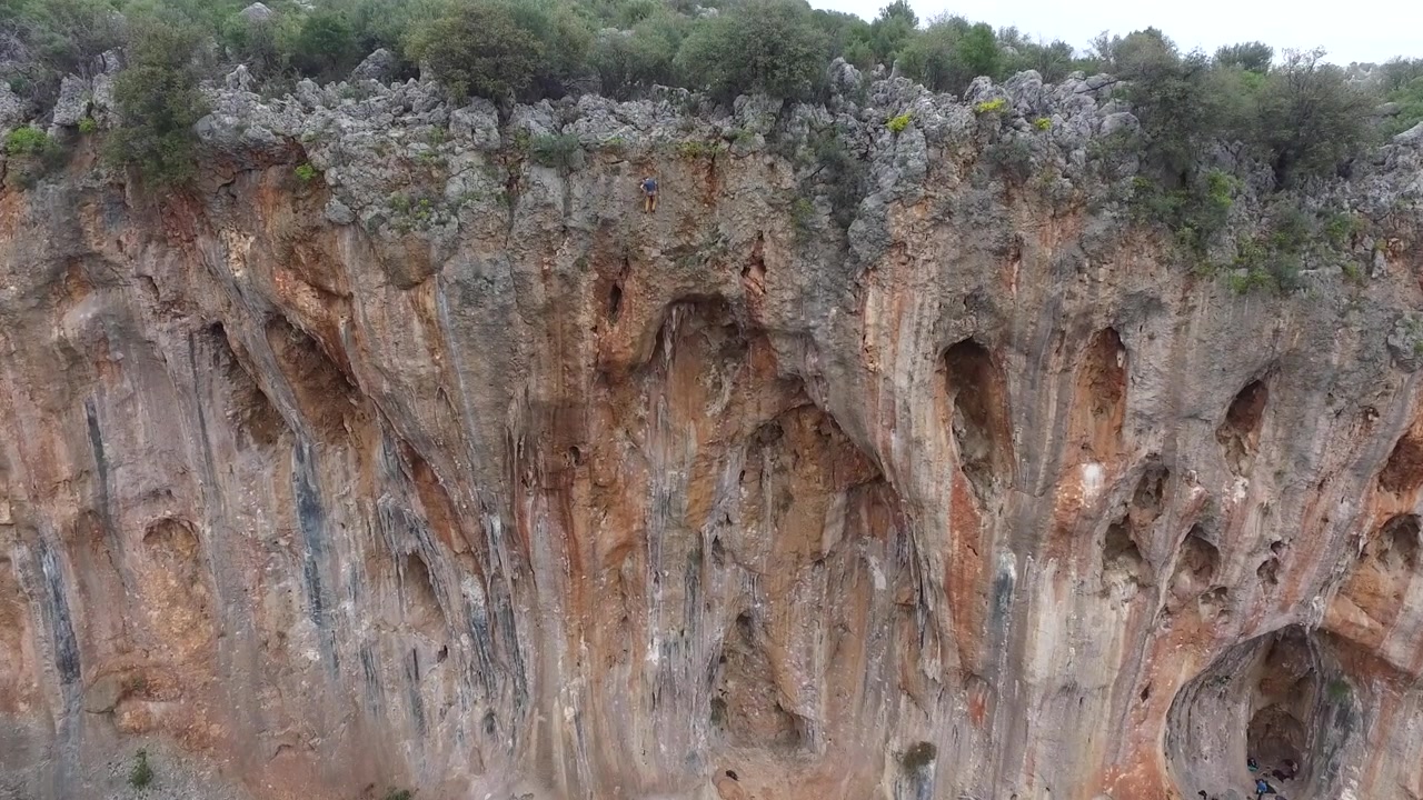 Scalatore di roccia che ascende una ripida parete di scogliera calcarea.