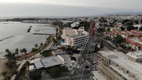 Aerial-close-up-of-a-construction-crane-with-city-and-coast-in-the-background