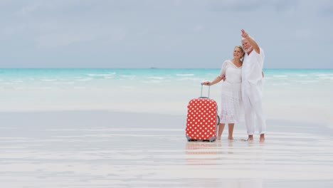 male female caucasian seniors on beach with suitcase