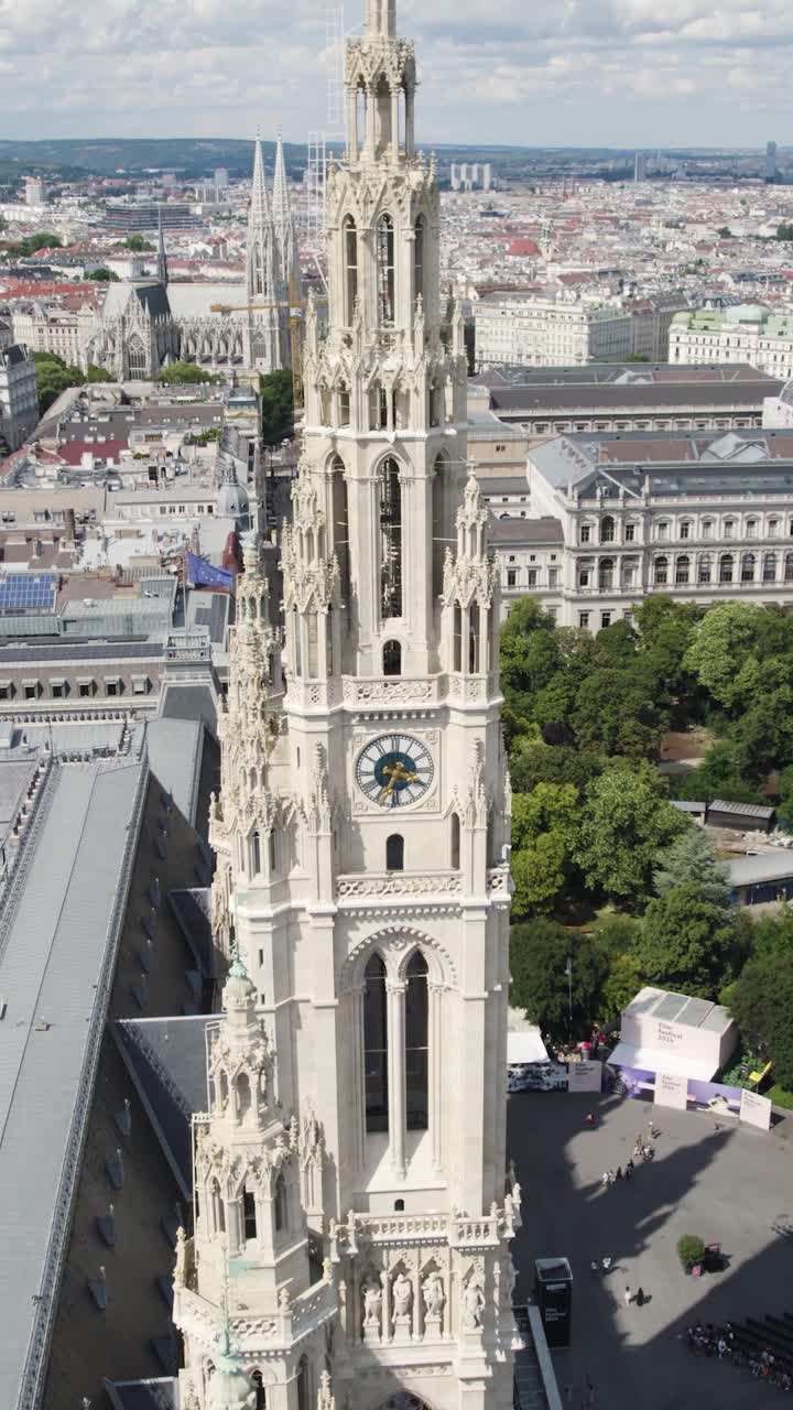 Aerial view of the neo gothic architecture of Vienna's Rathaus, showcasing its intricate details and clock tower against the backdrop of the city. Vertical Video