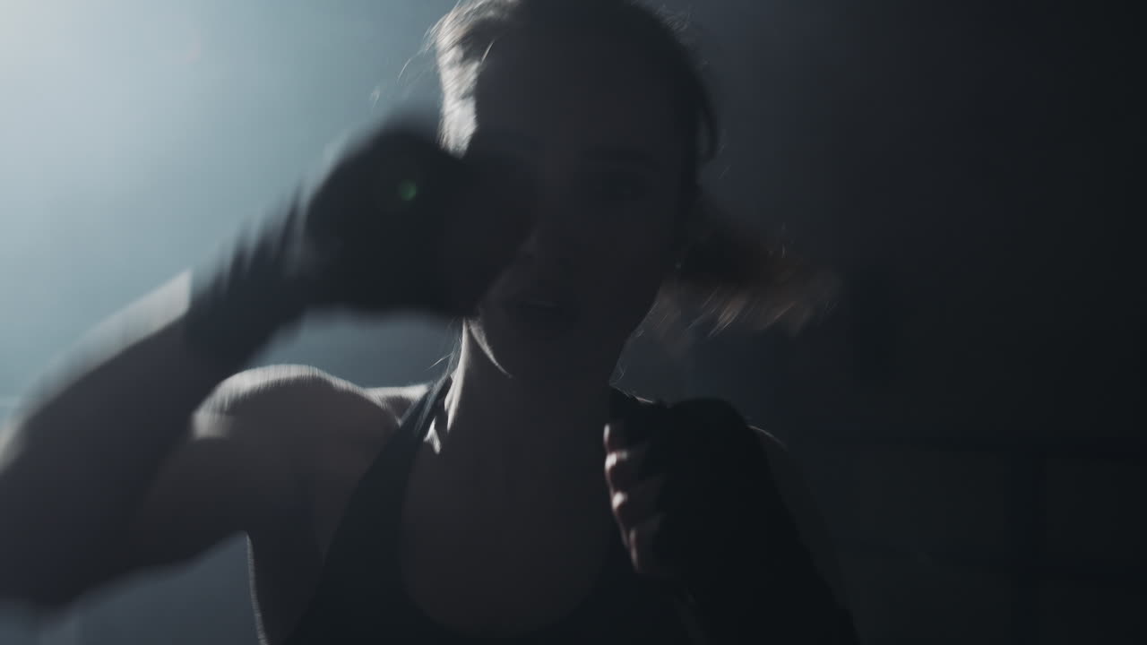 Female Boxer Training in a Dimly Lit Gym