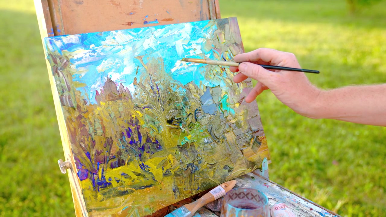 Mano d'artista che dipinge un paesaggio vivace su tela all'aperto