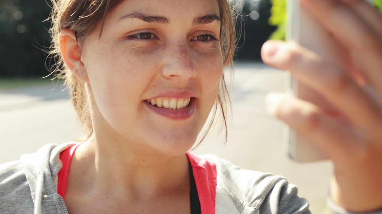 휴대 전화 공유와 함께 야외에서 비디오 메시지를 보내는 여성