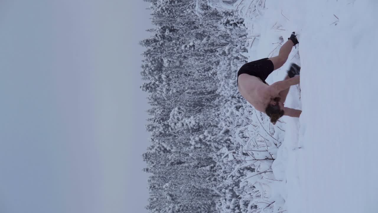 un hombre está haciendo un handstand en el medio de la nieve profunda - tiro vertical