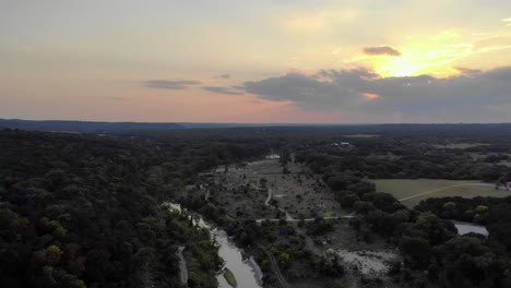 descenso aéreo sobre campos, árboles, - río al atardecer
