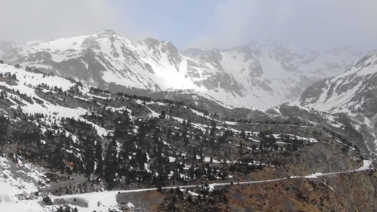 Aerial view of snowy mountain pass road with light snowfall, Ordino Arcalis, Andorra