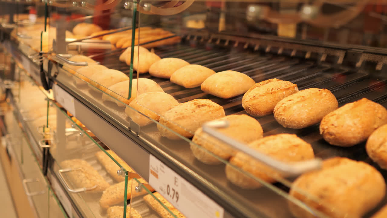 Rows of golden baked bread on tray in commercial bakery under warm lighting