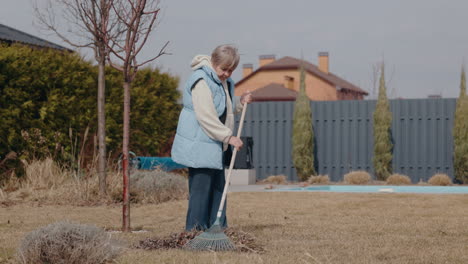 elderly woman raking leaves in backyard garden