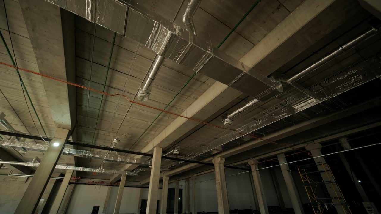 Ventilation pipes in silver insulation material hanging from the ceiling inside new building.