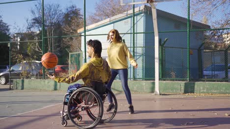 disabled man in wheelchair playing basketball with his young girlfriend.