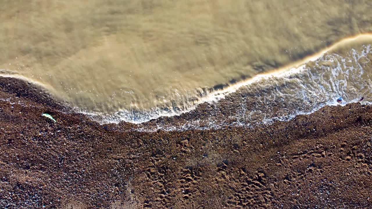 olas turbias de agua de mar golpeando la playa de guijarros en la costa de kent de la bahía de herne en el reino unido