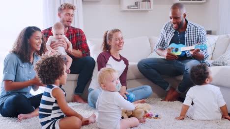 friends with toddlers playing and singing on floor and sofa