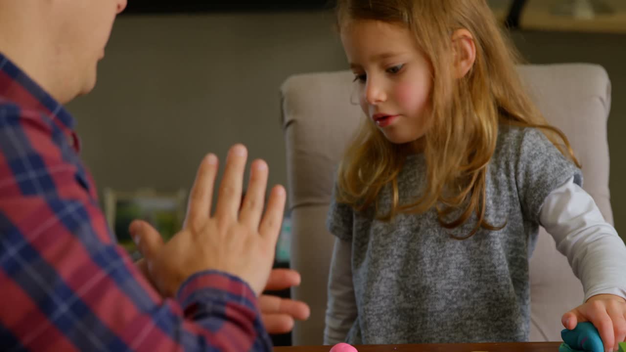 Father and daughter playing with clay in living room 4k