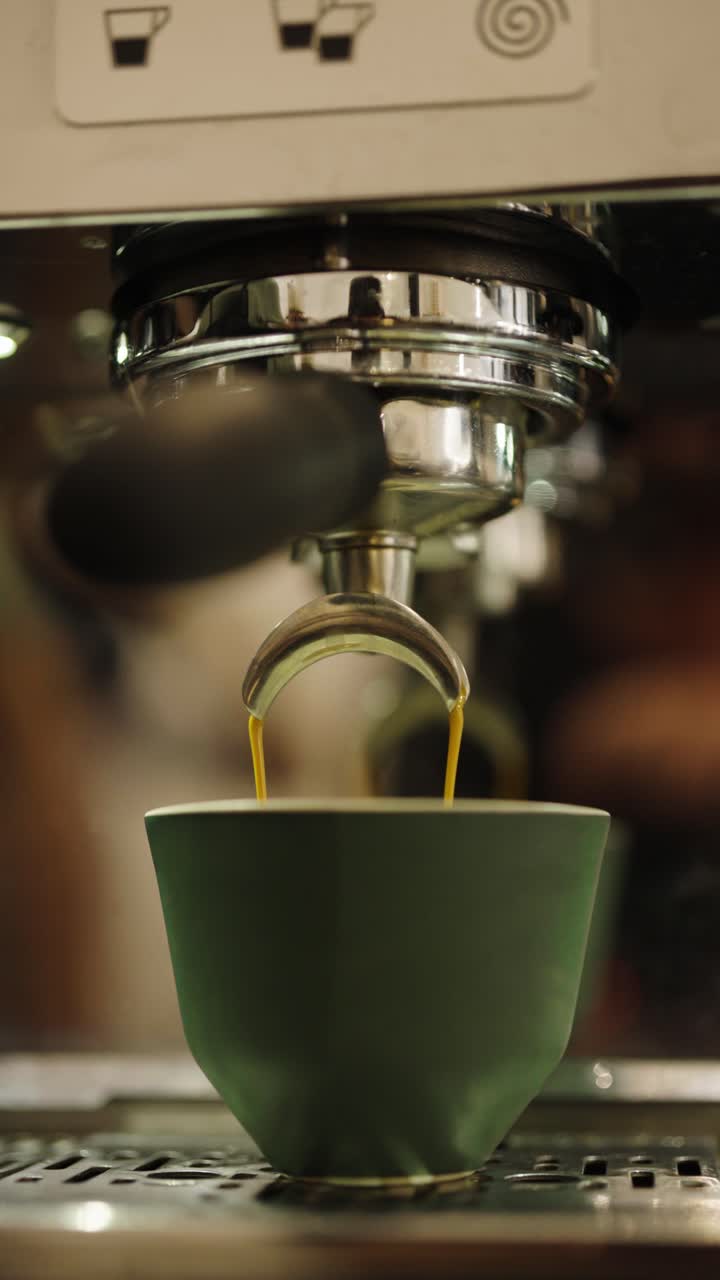 Vertical close up of black coffee flow into cup from machine, Czechia