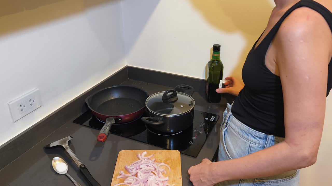 Woman cooking with onions and olive oil in the kitchen