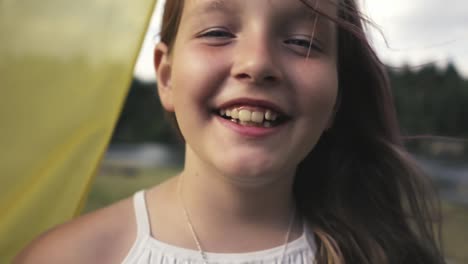 Portrait-of-an-eight-year-old-blonde-girl-laughing-on-a-grassy-beach-on-a-sunny-summer-day