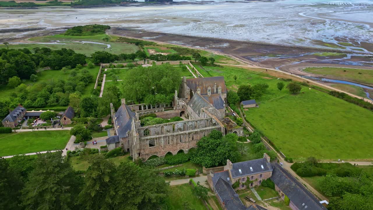 Sideways drone movement around the gothic Abbaye de Beauport historic abbey near tidal flats and countryside, Paimpol, Brittany, France.