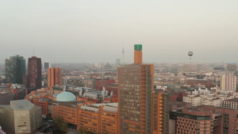 Backwards-reveal-of-modern-multistorey-buildings-in-Potsdamer-Platz-area.-Hot-air-balloon-and-Fernsehturm-TV-tower-in-distance.-Berlin,-Germany