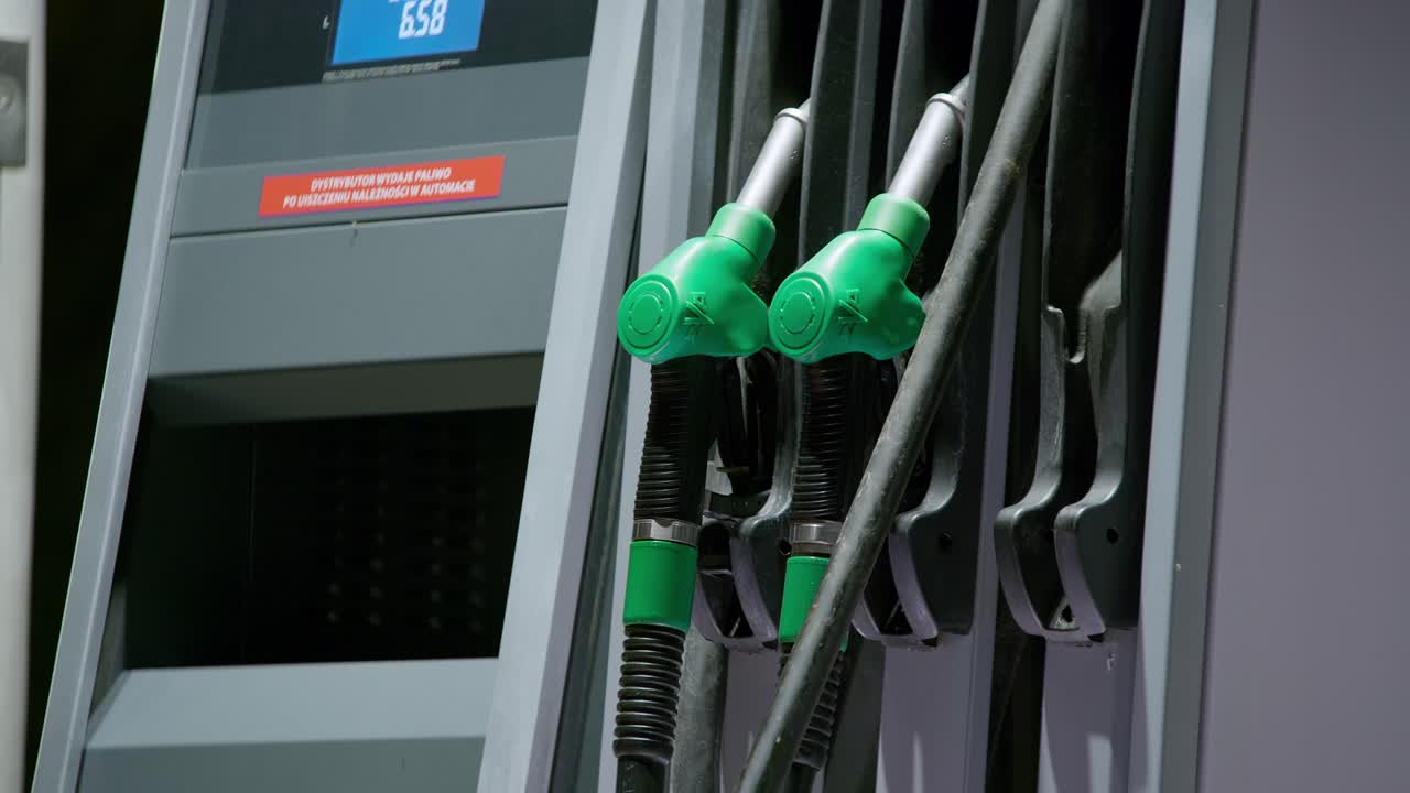 한 사람이 주유소에서 자동차 탱크에 연료를 보급하기 위해 디젤 연료 핸들을 집어 들었습니다.