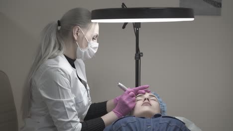 beautician colours visitor eyebrow in black against wall