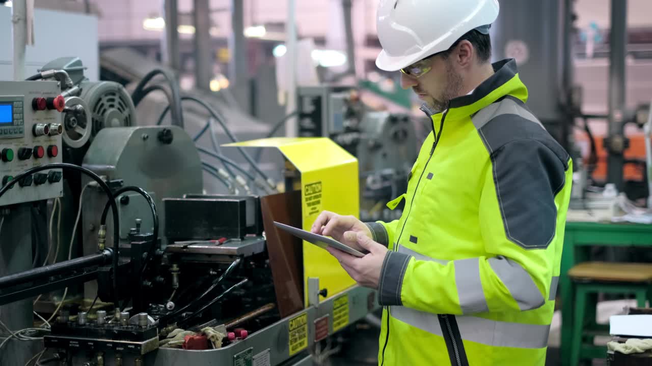 Shot of Professional Factory Worker Wearing Hard Hat Holds Tablet Computer, Walking Thorugh Modern Industrial Manufacturing Facility