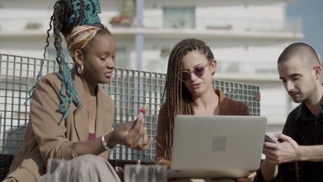 front view of coworkers looking at laptop screen outdoor