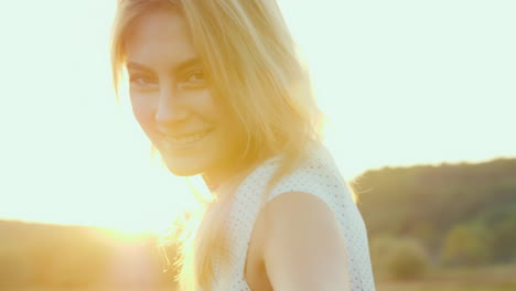 portrait of a beautiful young woman at sunset orange light highlights her hair behind