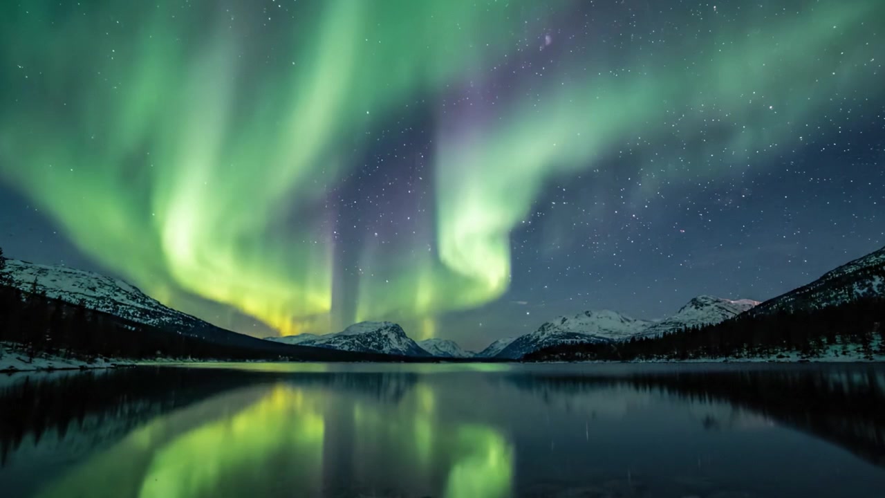 Spettacolare esibizione dell'aurora boreale che si riflette su un lago sereno sotto un cielo notturno stellato, catturando la magia delle meraviglie celesti della natura.
