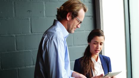 businessman discussing with businesswoman over digital tablet